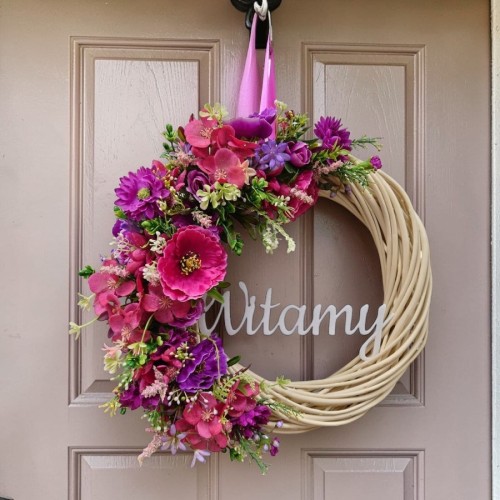 wianek wiklinowy na drzwi z napisem "witamy" z różowo fioletowymi kwiatami, średnica 33cm , napis biały akrylowy, na tle drzwi